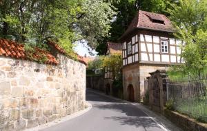an alley with a building next to a stone wall at Ferienhaus Villa Korn in Ebern