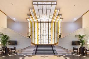 ダクスにあるHotel & Spa Vacances Bleues Le Splendidの階段と大きな窓のあるロビー