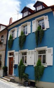 a blue building with white windows and plants at Ferienhaus Finster in Volkach