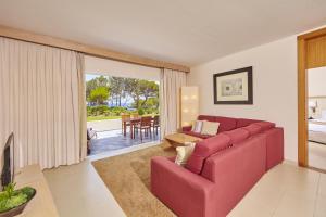 a living room with a red couch and a table at Blau PortoPetro Beach Resort & Spa in Portopetro