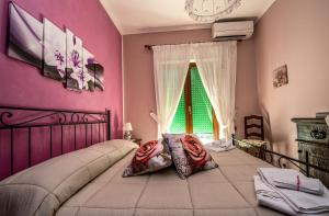 - une chambre avec un lit aux murs roses et une fenêtre dans l'établissement Il Fiore del Golfo, à SantʼAgata sui Due Golfi