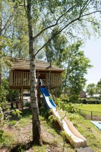 a playground with a slide in front of a house at Boerderijcamping de Berghoeve in Ruinen
