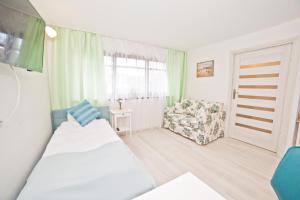 ソポトにあるLa Playa by Grand Apartmentsのベッドと椅子付きの小さな部屋です。