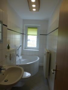La salle de bains est pourvue d'une baignoire, d'un lavabo et d'une fenêtre. dans l'établissement Ferienwohnung Fichtelberg, à Kurort Oberwiesenthal