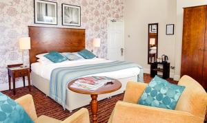 a hotel room with a bed and two chairs at White Swan Hotel in Alnwick