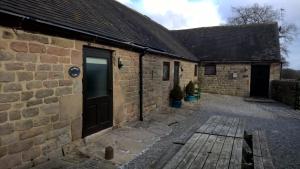 a brick building with a door and a bench in front at Warren Carr Courtyard Barn in Stanton in Peak