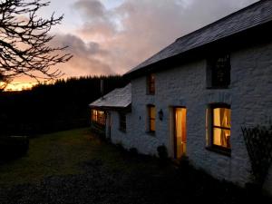 a stone house with a sunset in the background at Bryngolau in Brechfa