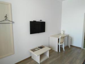 a white room with a table and a tv on a wall at Vekar Guest House in Sochi