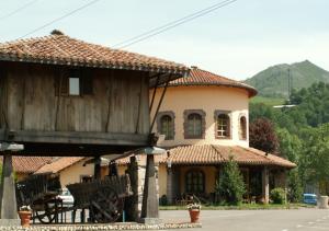 a large house with a building with a roof at Hotel El Bricial in Soto de Cangas