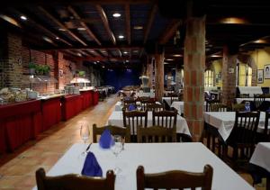 a restaurant with white tables and chairs and a bar at Hotel El Bricial in Soto de Cangas