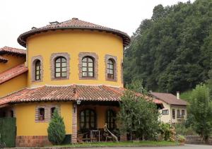 a yellow house with a tiled roof at Hotel El Bricial in Soto de Cangas