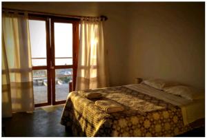 a bedroom with a bed and a large window at Altavista Casa de Huespedes in Vichayito