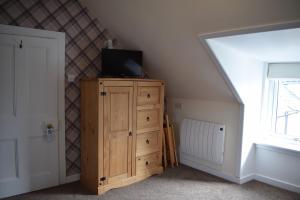 una camera con cassettiera in legno e TV in cima di The Tables Guest House a Dunvegan