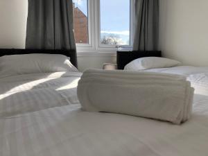a bedroom with two beds with white sheets and a window at Glenrothes Central Apartments - One bedroom Apartment in Glenrothes