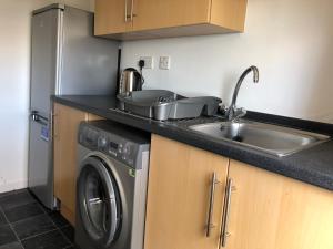 a kitchen with a sink and a washing machine at Glenrothes Central Apartments - One bedroom Apartment in Glenrothes