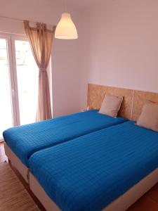 a bedroom with a large blue bed with a window at Fisherman's House in Aljezur