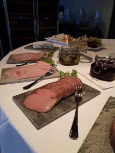 una mesa con tres platos de carne y un tenedor en Bjerkeløkkja Bed and Breakfast en Oppdal