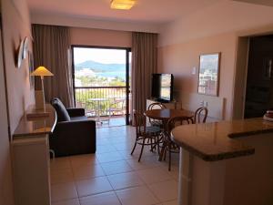 cocina y sala de estar con vistas a un balcón en Suítes e Studios no Hotel Jurerê Beach Village, en Florianópolis