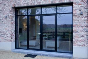 una finestra di vetro su un edificio in mattoni con un patio di Logies De Hessie a Turnhout