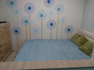 - une chambre avec un lit orné de fleurs bleues sur le mur dans l'établissement квартира-студия в центре, à Khmelnytsky