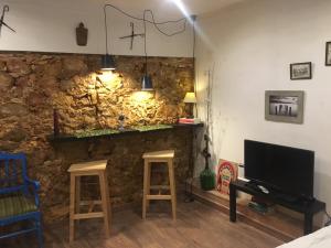 a room with a stone wall with two stools and a television at Quinta da Sao Joao - Villa Oliveira in Olhão