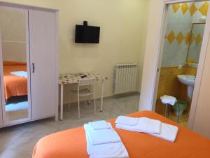 um quarto com uma cama laranja e toalhas em Albergo Oasi em Nápoles