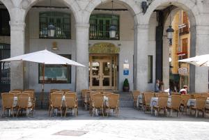 
an outdoor dining area with tables, chairs and umbrellas at Infanta Isabel by Recordis Hotels in Segovia
