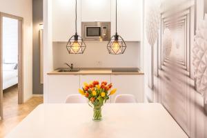 a white kitchen with a vase of flowers on a table at No.3 Apartment Link-To-Happiness in Klaipėda