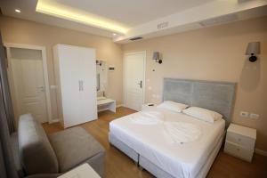 ein Schlafzimmer mit einem weißen Bett und einem Stuhl in der Unterkunft Hotel Edart in Durrës
