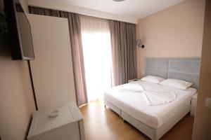 a bedroom with a white bed and a large window at Hotel Edart in Durrës