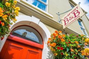 un negozio con un cartello sopra una porta rossa e fiori di Linsfort Guest House a Boyle