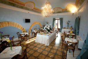 a dining room with tables and chairs and a chandelier at Hotel Carmine in Marsala