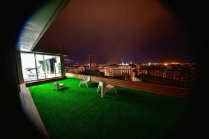 a balcony with green grass and white chairs at night at Zenit Don Yo in Zaragoza