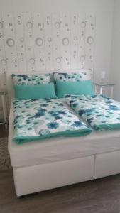 a white bed with blue sheets and pillows on it at Ferienhaus Gregor in Birkenwerder