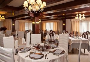 uma sala de jantar com mesas e cadeiras brancas e um lustre em San Marcos Salnés em Cambados