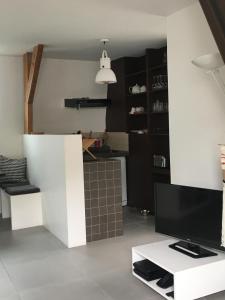 a living room with a television on a white table at L'étoile de Trouville in Trouville-sur-Mer