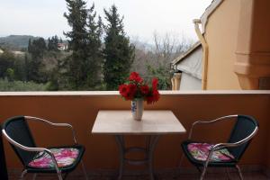 a table with two chairs and a vase of flowers on a balcony at Georgia Apartments & Studios Corfu in Glyfada