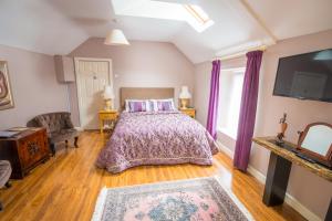 a bedroom with a bed and a tv and purple curtains at Linsfort Guest House in Boyle