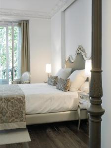 a white bedroom with a large bed with a table at Hospes Puerta de Alcalá, a Member of Design Hotels in Madrid