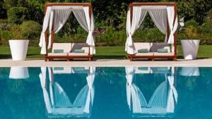 a pool with chairs and umbrellas in it at Hotel Quinta das Lagrimas - Small Luxury Hotels in Coimbra