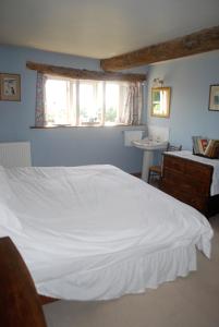 Grove Farm B&B في Newnham: غرفة نوم بسرير ابيض ونافذة