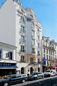 un gran edificio blanco con coches estacionados frente a él en Timhotel Tour Montparnasse, en París