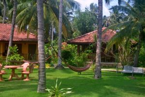 a hammock in the yard of a resort with palm trees at Puetz Travels Beach Resort in Waikkal