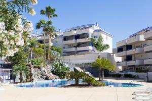 een gebouw met palmbomen en een zwembad bij El Ancla in Los Cristianos