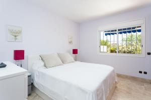 een witte slaapkamer met een wit bed en een raam bij El Ancla in Los Cristianos +39 foto's