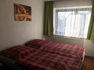 a bed in a bedroom with a red plaid blanket at Ferienwohnung Fam.Stecher in Malschwitz