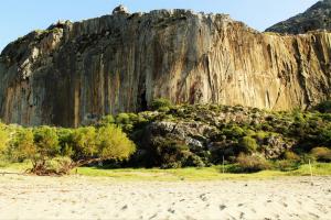 a large cliff with a tree in front of a beach at Paligremnos Studios in Plakias