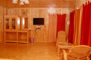 a living room with red curtains and a tv at Surya Holidays Kodaikanal in Kodaikānāl