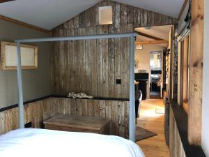 a bedroom with a wooden wall with a bed at Faraway Follies in Llandegla