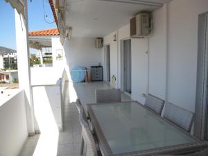 uma mesa de vidro e cadeiras numa varanda em Seaside Modern Apartment - Explore Athens and Beyond em Porto Rafti